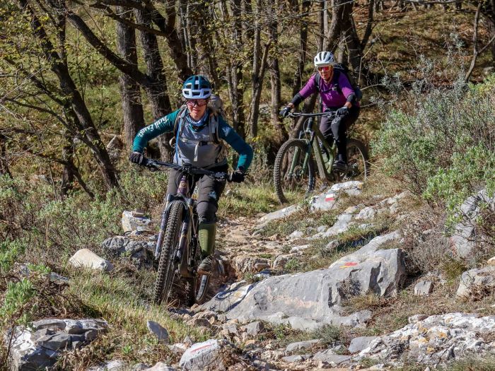 Zwei Bikerinnen unterhalten sich lachend vor rotem Gebäude